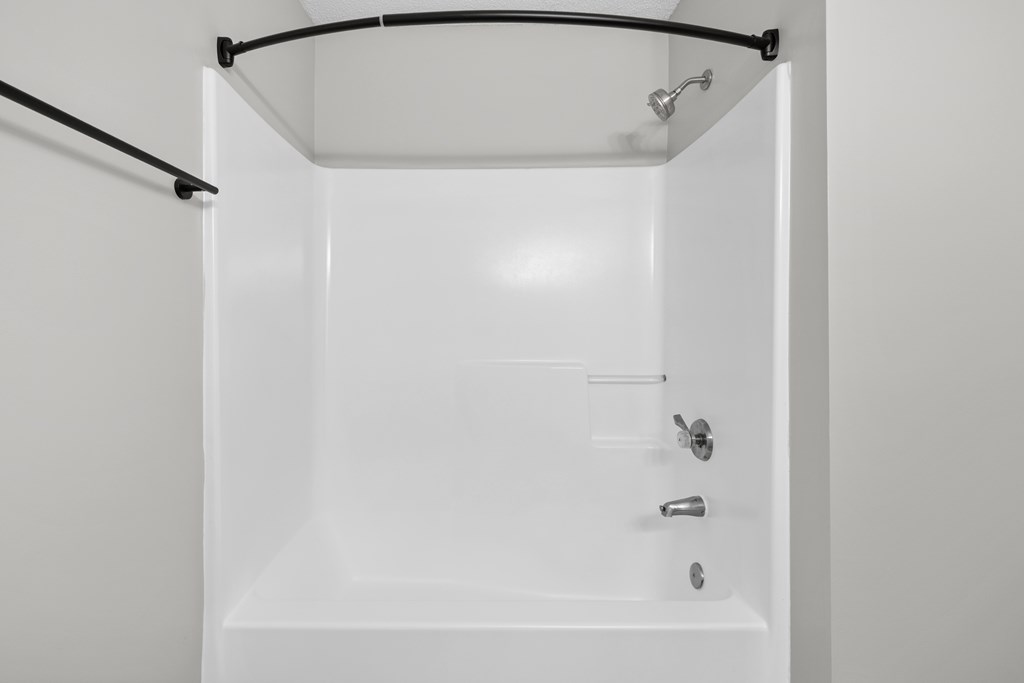 A white bathroom with a tub and a towel rack.