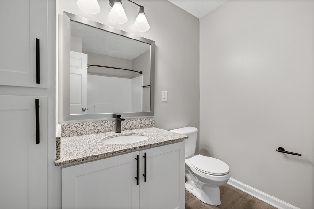 A white bathroom with a toilet, sink, and mirror.