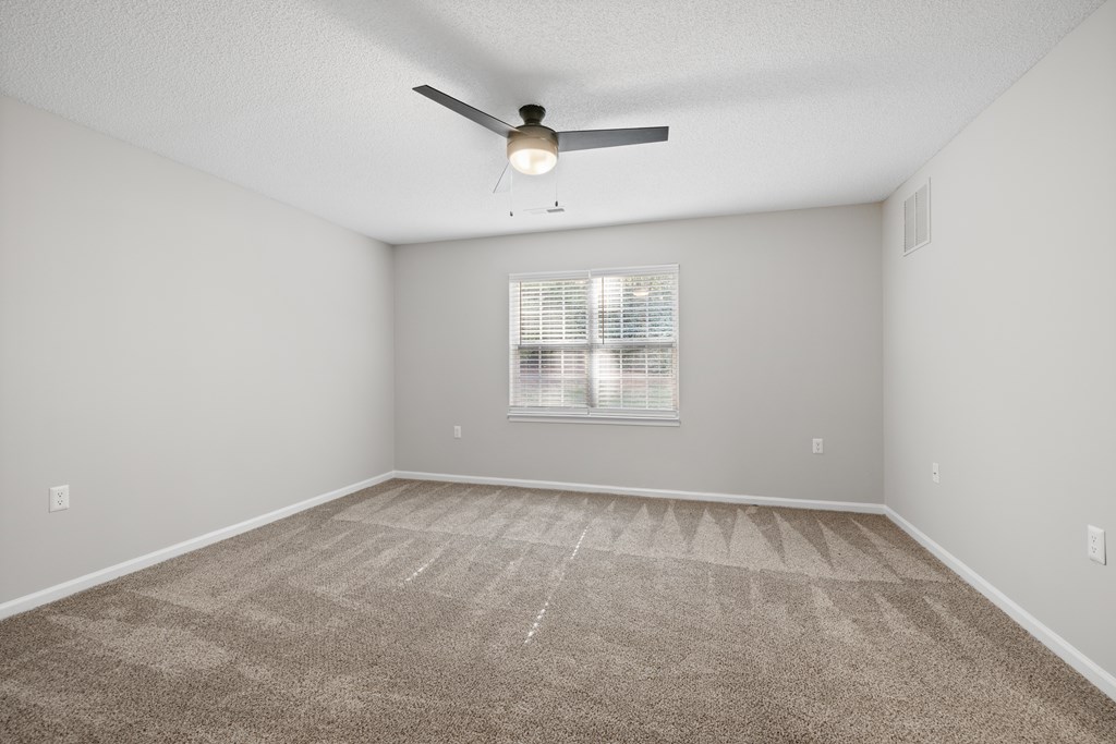 A room with a ceiling fan and carpeted floor.