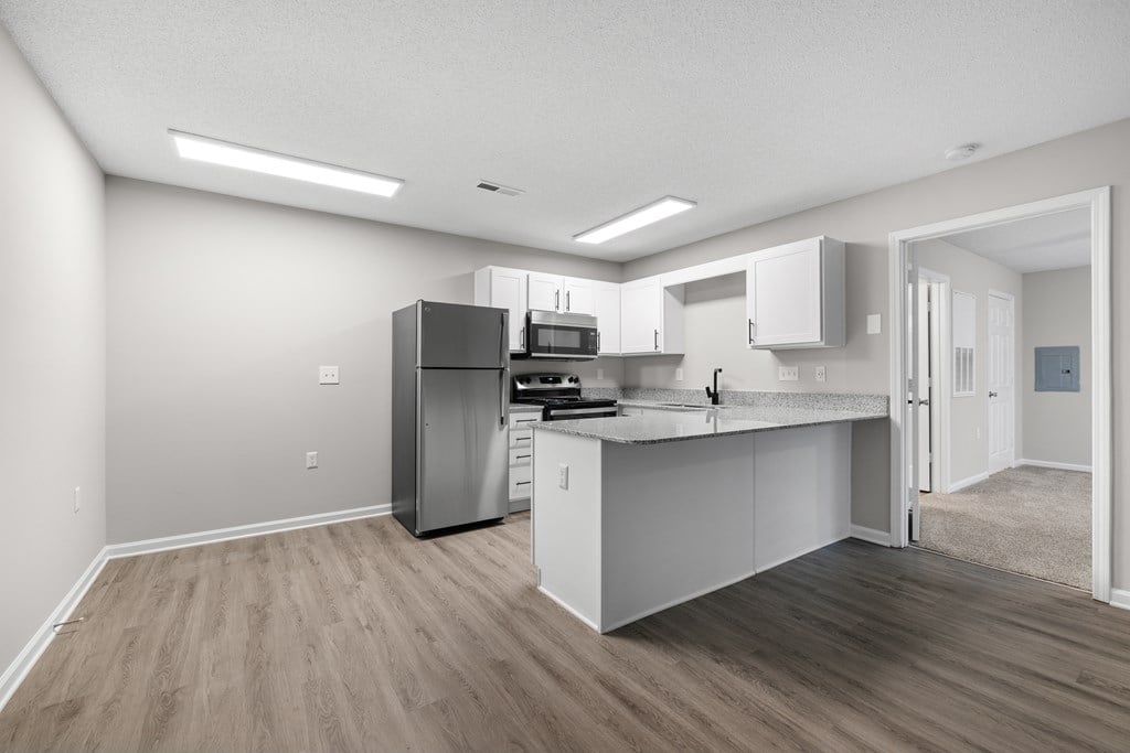 A kitchen with white cabinets and a wooden floor.