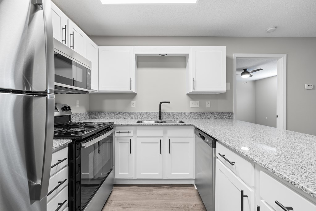 A modern kitchen with white cabinets and stainless steel appliances.