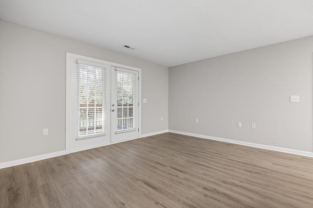 A room with a sliding glass door and wooden flooring.