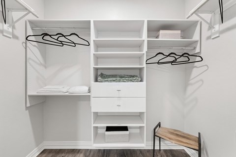 A white closet with a bench and a hanging rod.