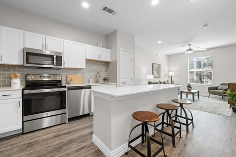 A kitchen with white cabinets and a white island with bar stools.