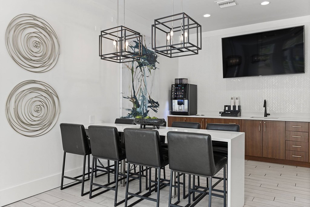 A modern kitchen with a white countertop and black chairs.