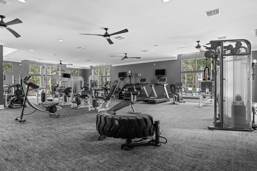 A gym with a variety of equipment including treadmills, weights, and exercise machines.