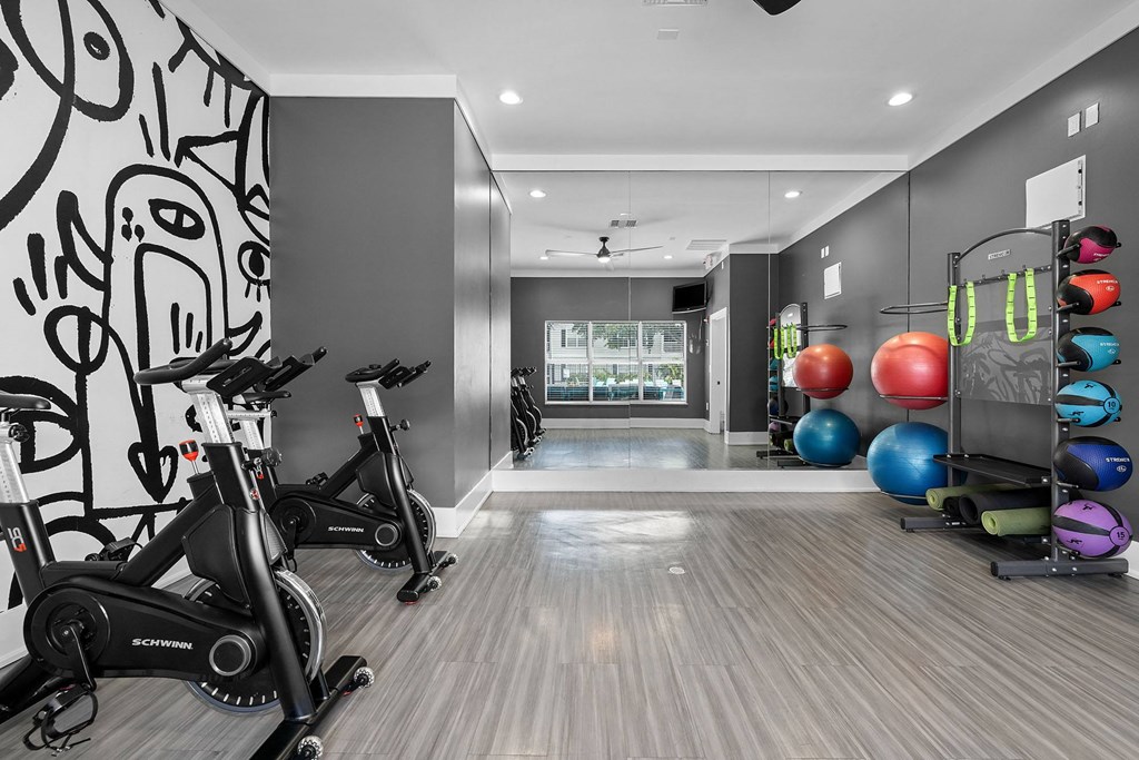 A room with exercise equipment and a wall with drawings.