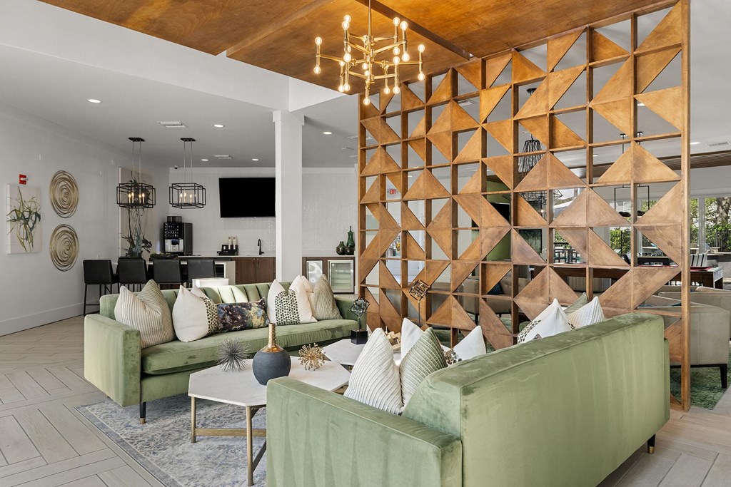 A living room with a wooden geometric wall panel and green couches.