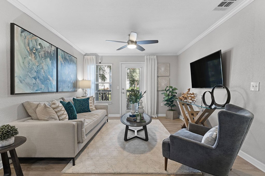 A living room with a grey couch, a black chair, a coffee table, and a painting on the wall.