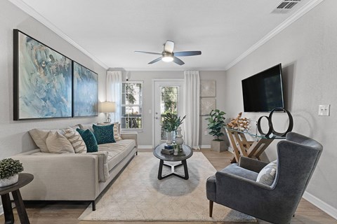 A living room with a grey couch, a black chair, a coffee table, and a painting on the wall.