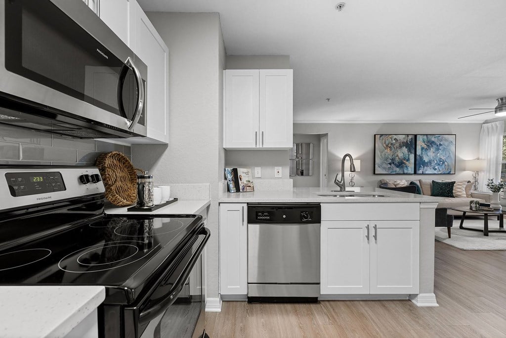 A modern kitchen with a black stove top oven and white cabinets.