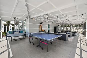 A ping pong table is in the middle of a room with a white ceiling and grey floor.