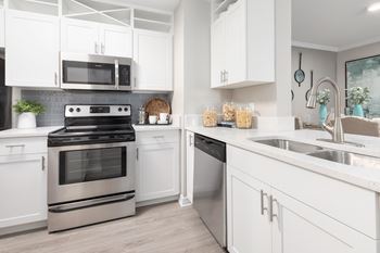 A modern kitchen with white cabinets and stainless steel appliances.