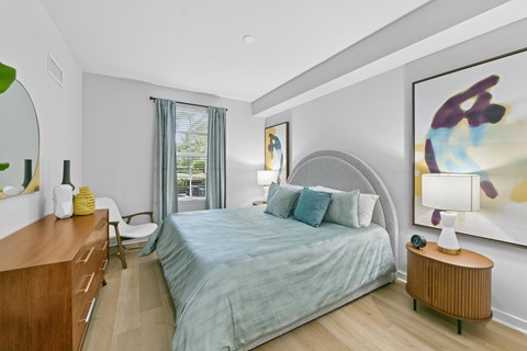 A bedroom with a bed, nightstand, and a painting on the wall.