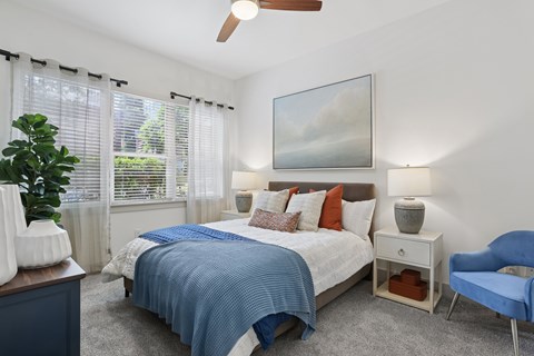 A bedroom with a bed, chair, and painting on the wall.