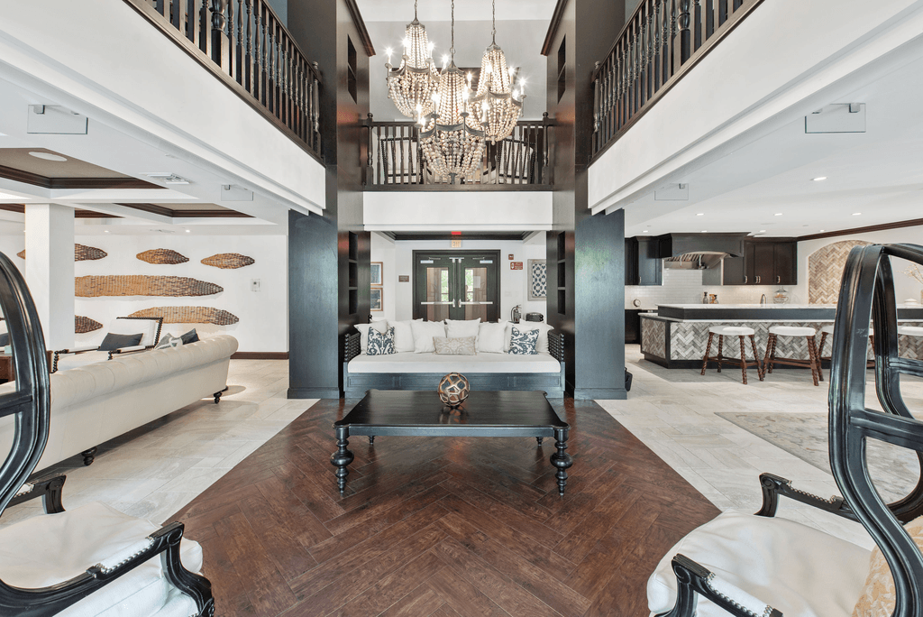 A large, elegant living room with a chandelier, a coffee table, and a staircase.