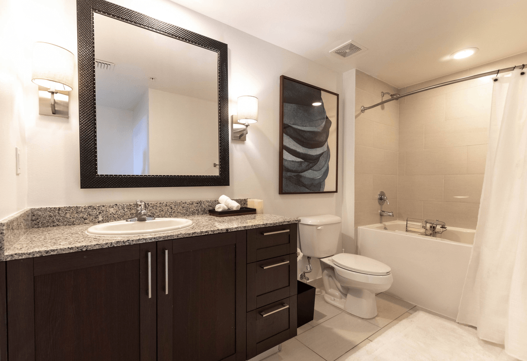 A bathroom with a white toilet, sink, and a large mirror.