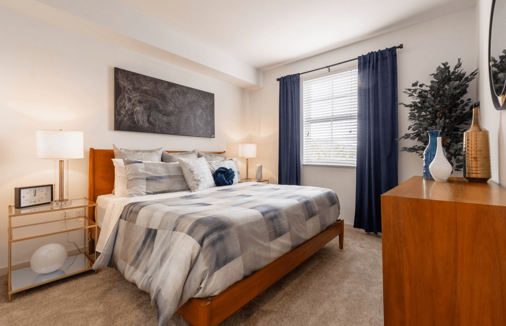 A bedroom with a bed, nightstand, and a painting on the wall.