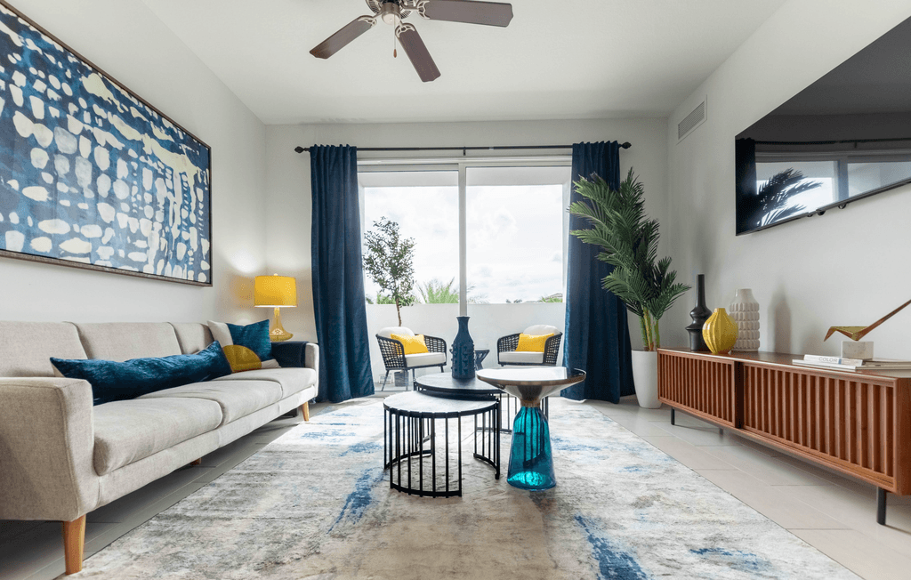 A living room with a beige sofa, a round table, and a painting on the wall.