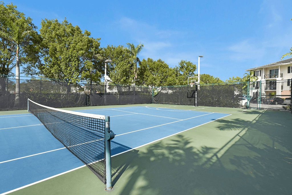 A tennis court with a net and trees in the background.