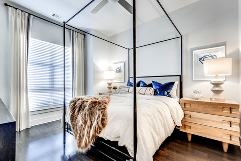 A bedroom with a four poster bed and a wooden nightstand.