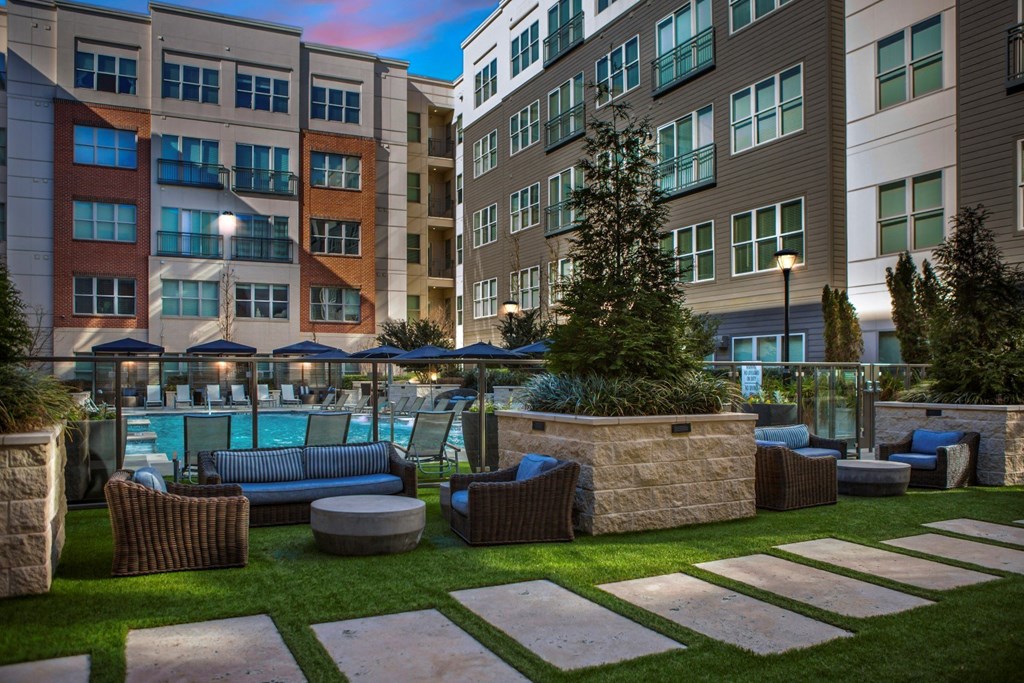 A pool surrounded by a stone wall and seating area.