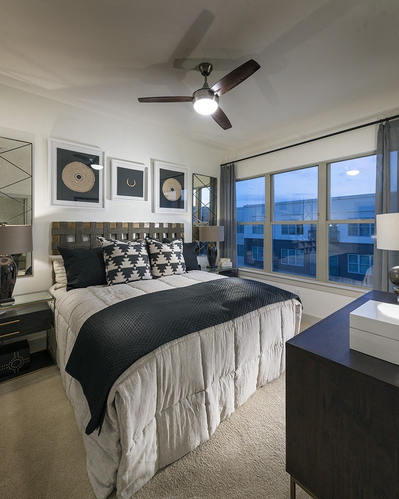 A bedroom with a large bed and a ceiling fan.