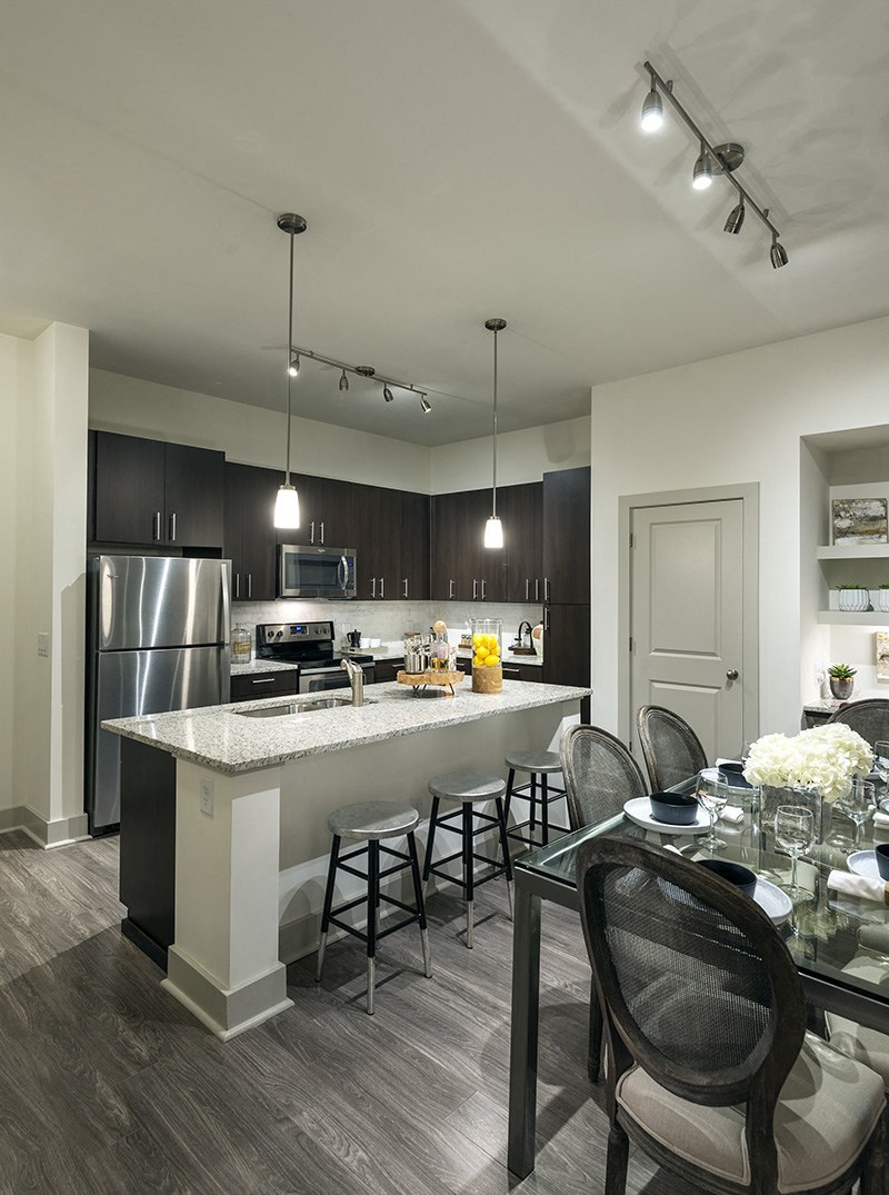 A modern kitchen with a bar area and a dining table set for two.
