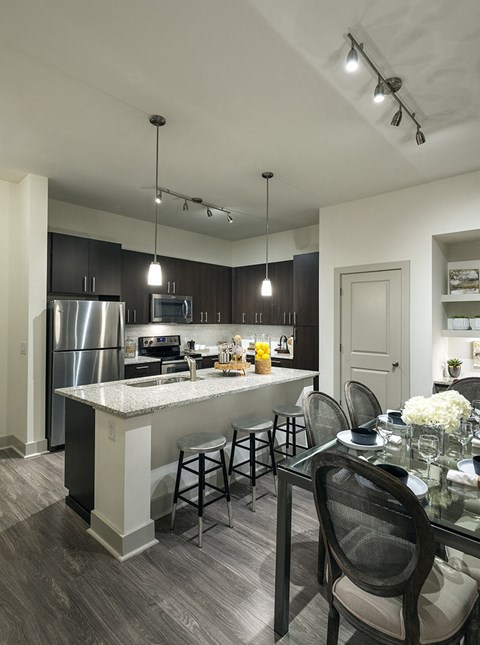 A modern kitchen with a bar area and a dining table set for two.