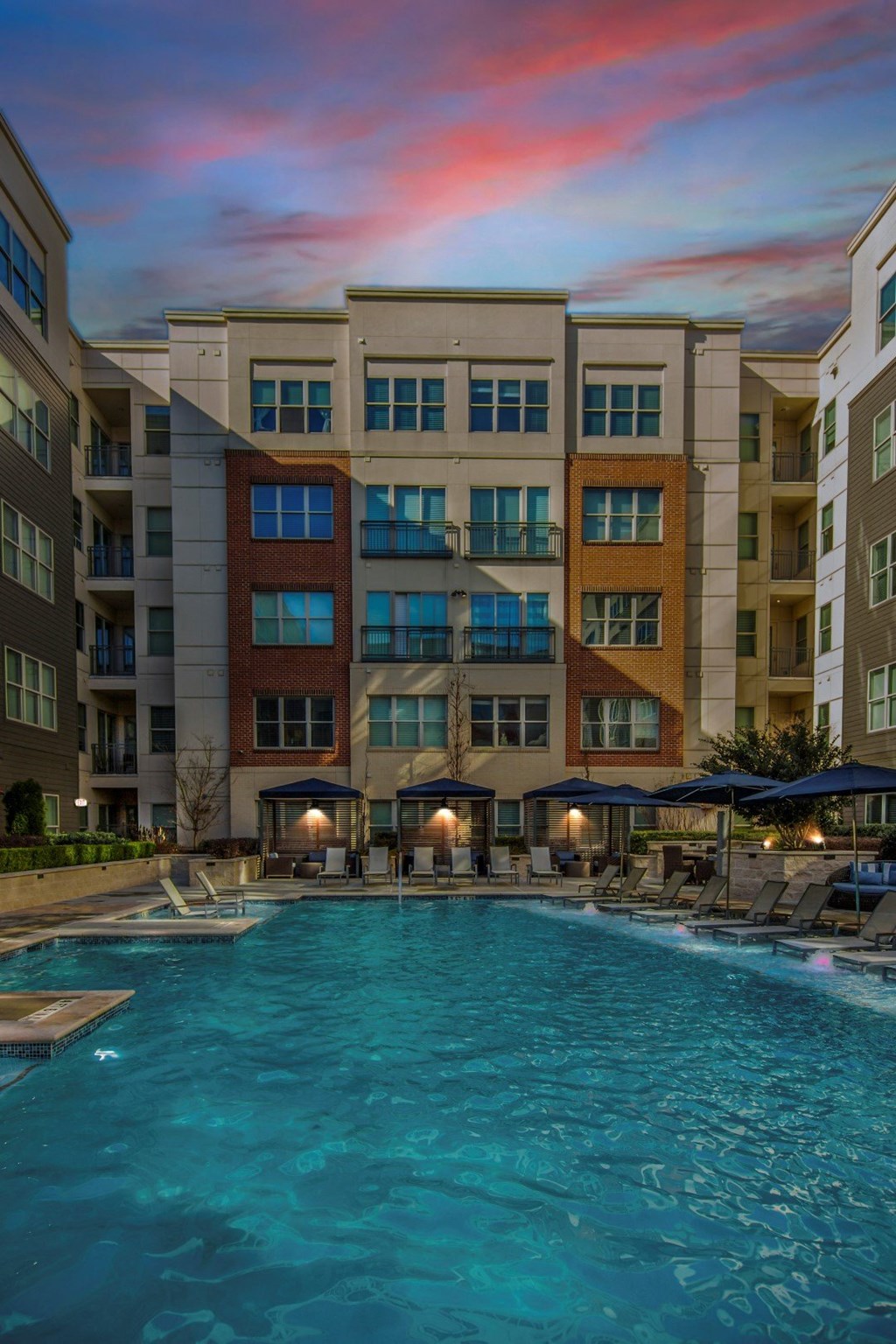 A swimming pool in front of a multi-story apartment building.