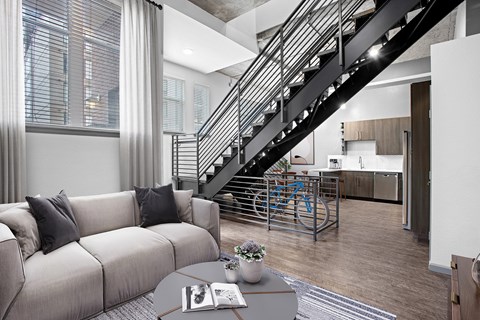 A living room with a grey couch and a bicycle in the background.