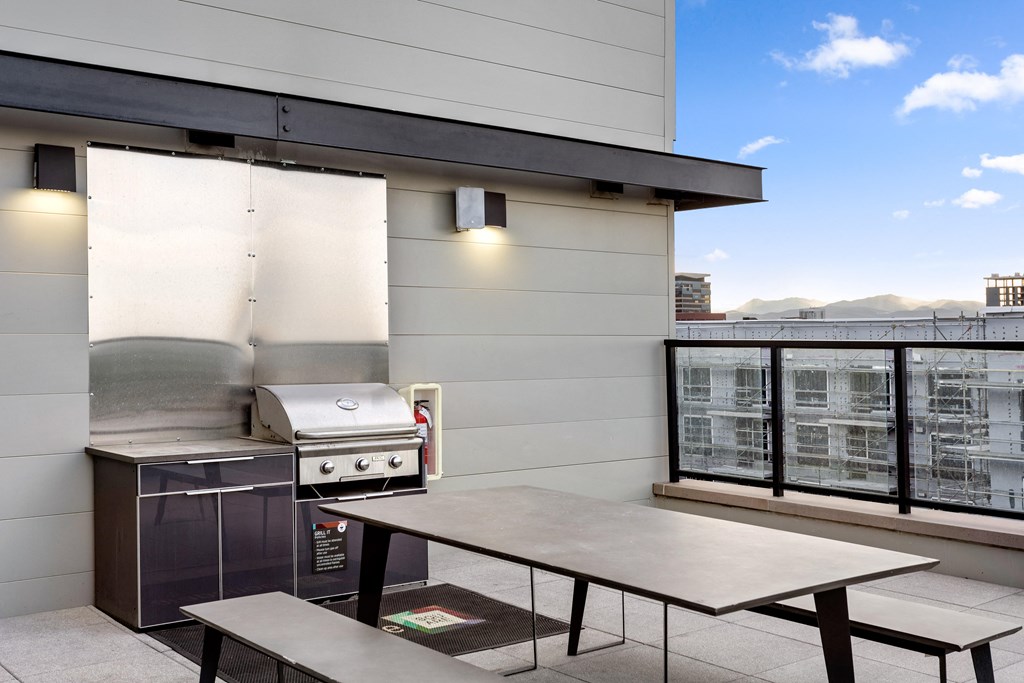 an outdoor patio with a grill and a table with benches