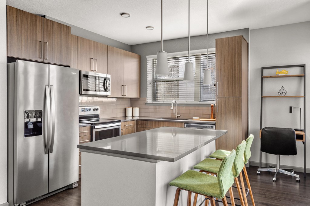 a kitchen with a large island and a stainless steel refrigerator
