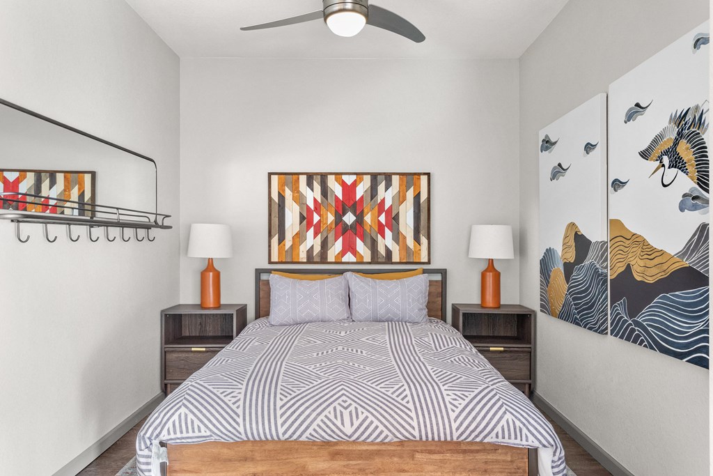 a bedroom with a bed and paintings and a ceiling fan