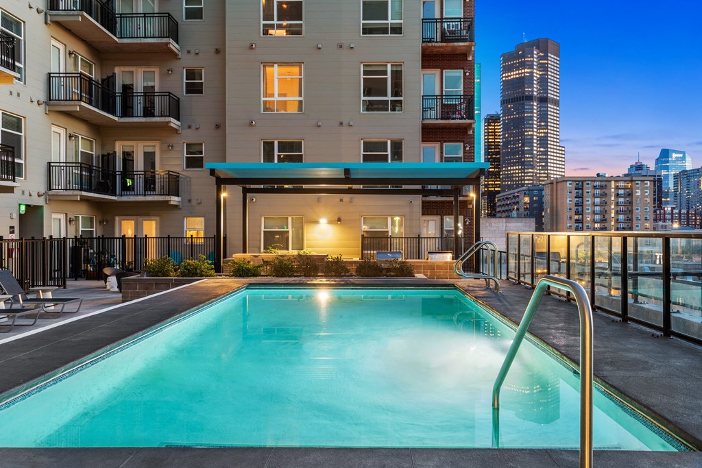 a swimming pool on the rooftop of an apartment building with a city view
