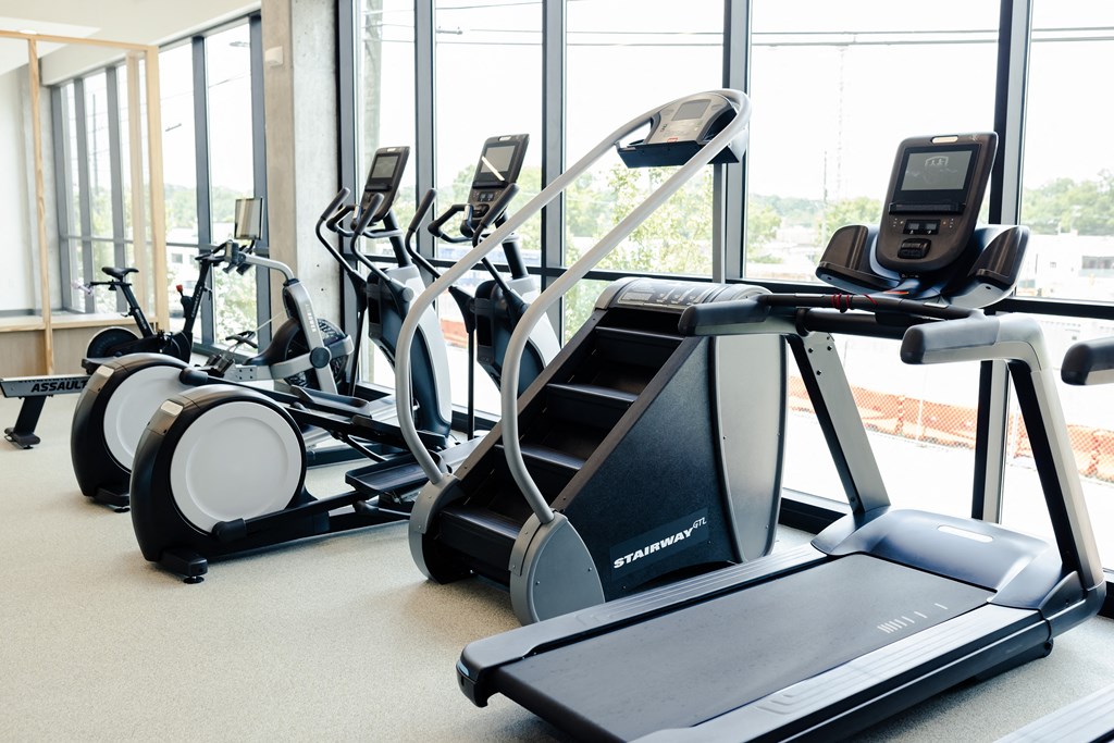 a row of treadmills and ellipticals in a gym