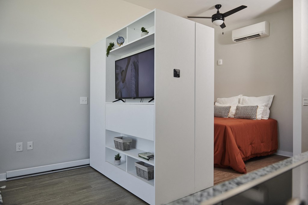 a cabinet with a television in a room with a bed