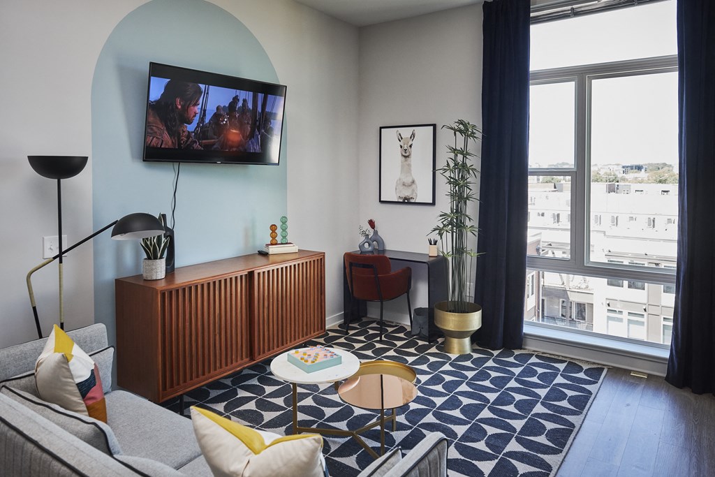 a living room with a blue and white rug and a television on the wall