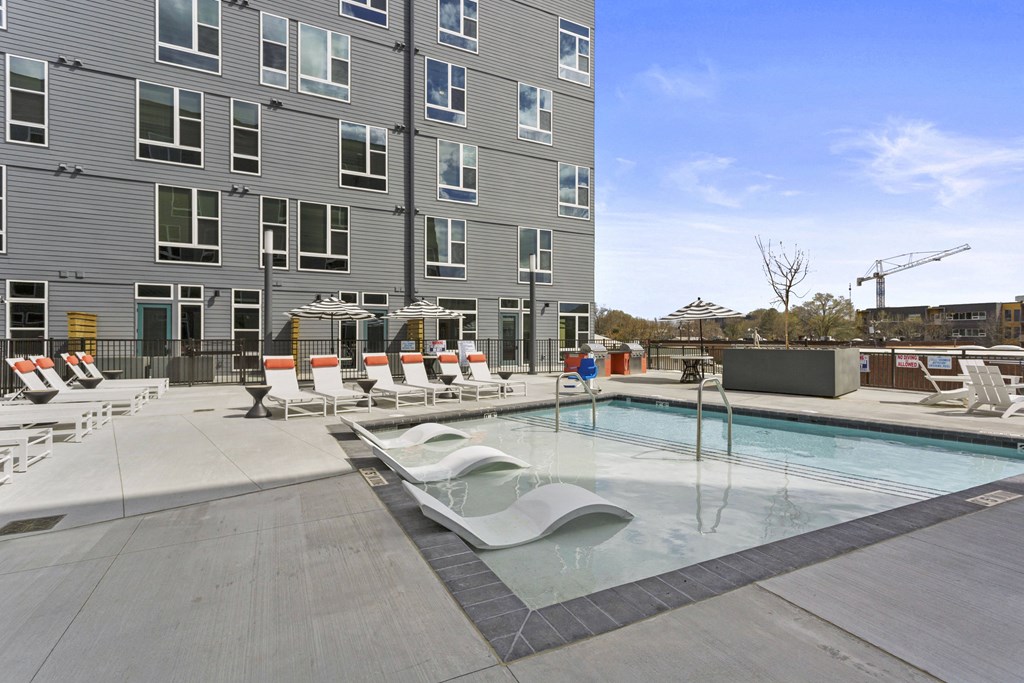 a pool with chairs and a building in the background