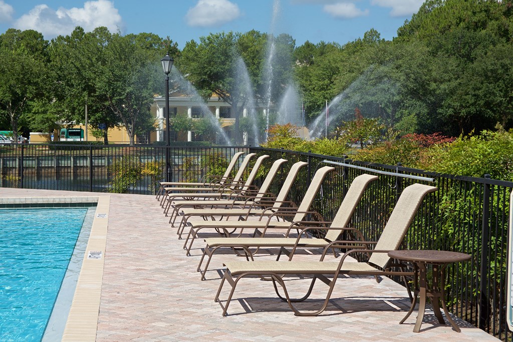 a row of chaise lounge chairs next to a pool