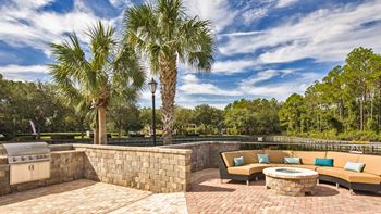 a patio with couches and a fire pit and palm trees