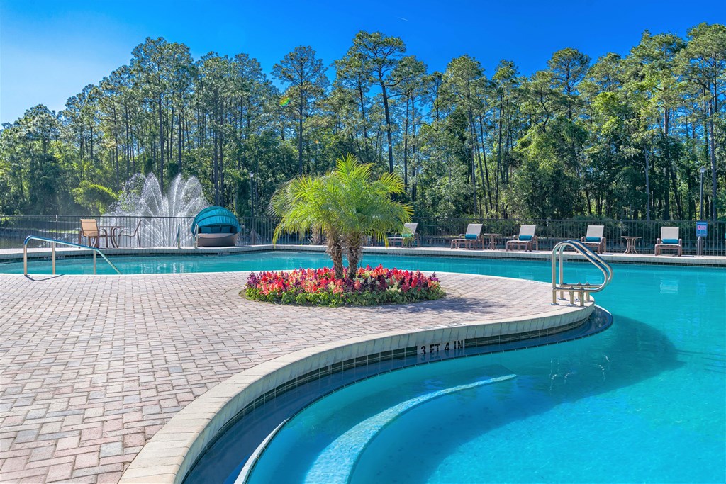 A pool with a palm tree next to it on a concrete path.
