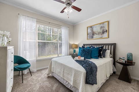 A bedroom with a bed, chair, and a ceiling fan.