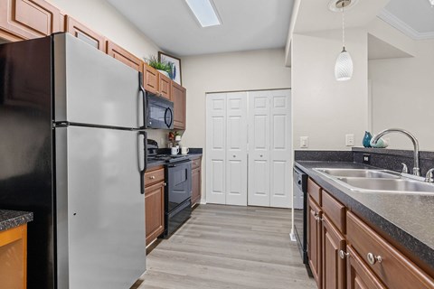 A kitchen with a black refrigerator and wooden cabinets.