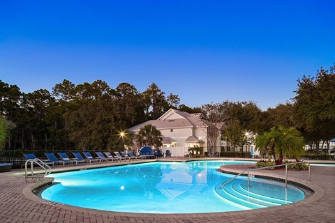 A swimming pool surrounded by trees and lounge chairs.