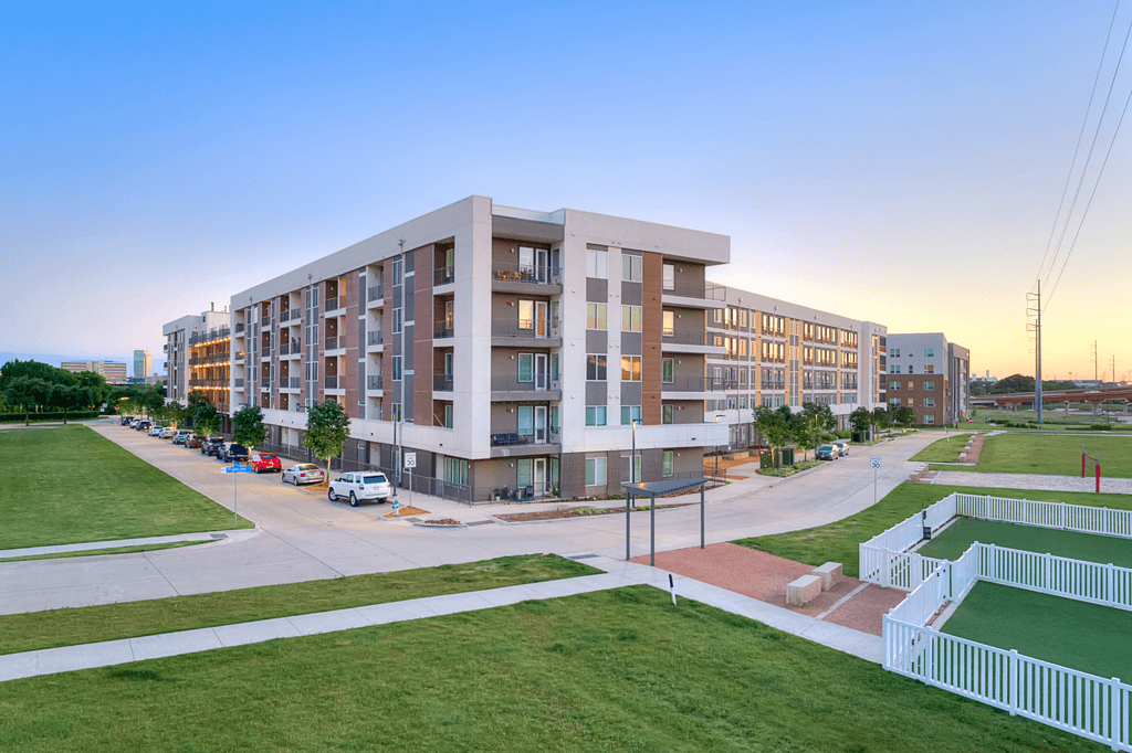 A modern apartment building with a parking lot in front.