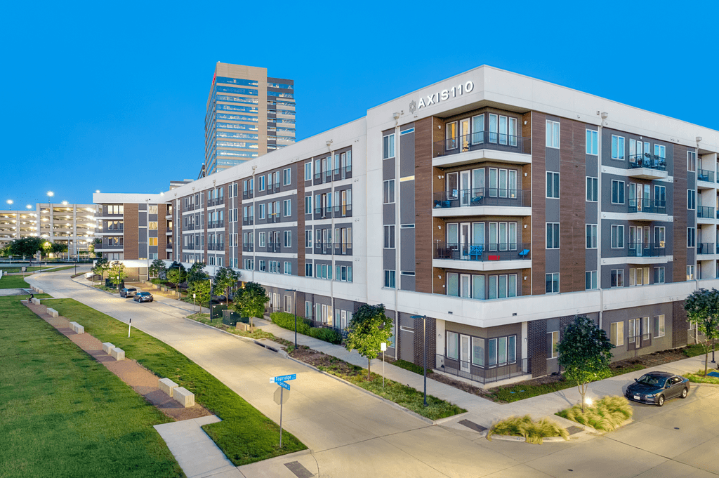 A modern apartment building named Axiisio is shown with a clear blue sky in the background.