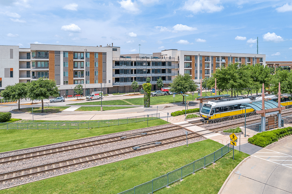 A train is passing by a building with a yellow sign.
