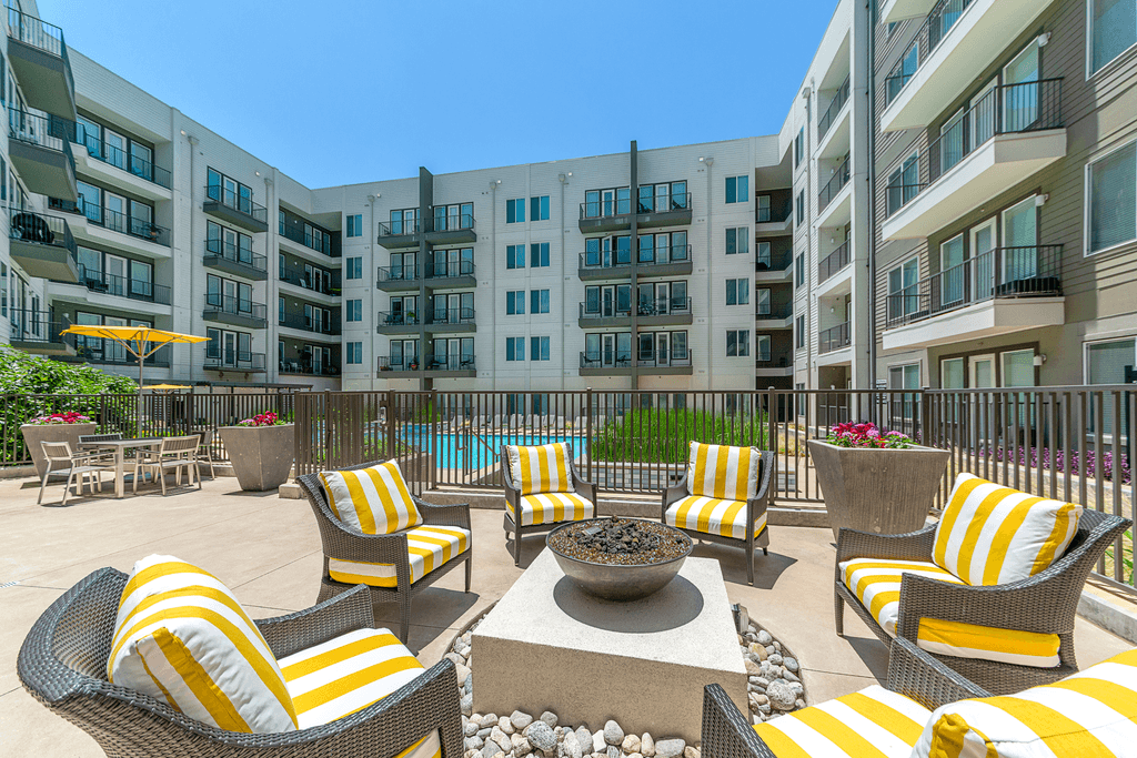A patio with yellow and white striped cushions and a fire pit.