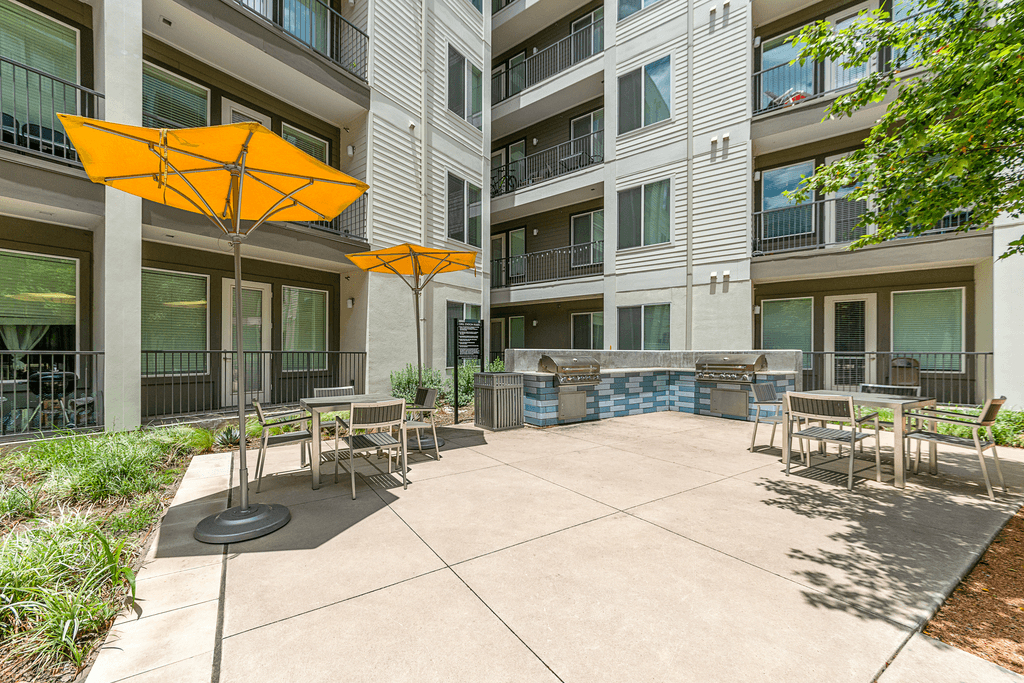 A patio area with a table and chairs and two umbrellas.